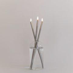 Everlasting candle made of silver colored metal rods in a glass container on a white background.
