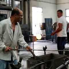 Two glass blowing artists working in a workshop.