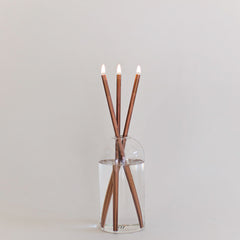 Everlasting candle made of 3 copper colored metal rods in a glass container